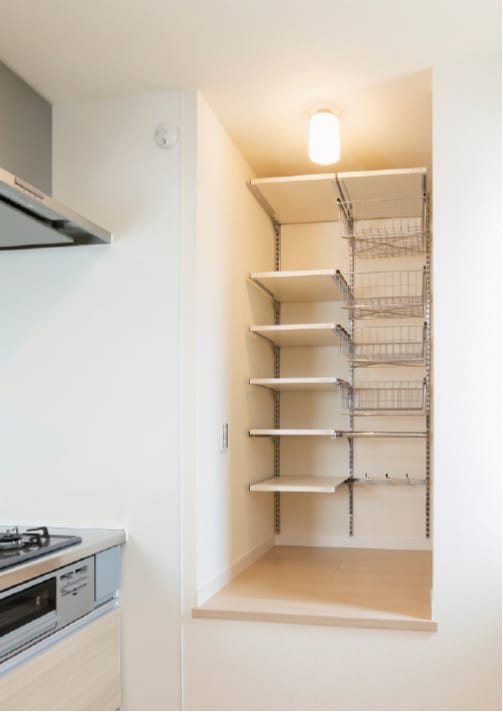 調理中に手の届く場所に、調味料や調理器具を収納する棚を設置。階段上のスペースを無駄なく活用。