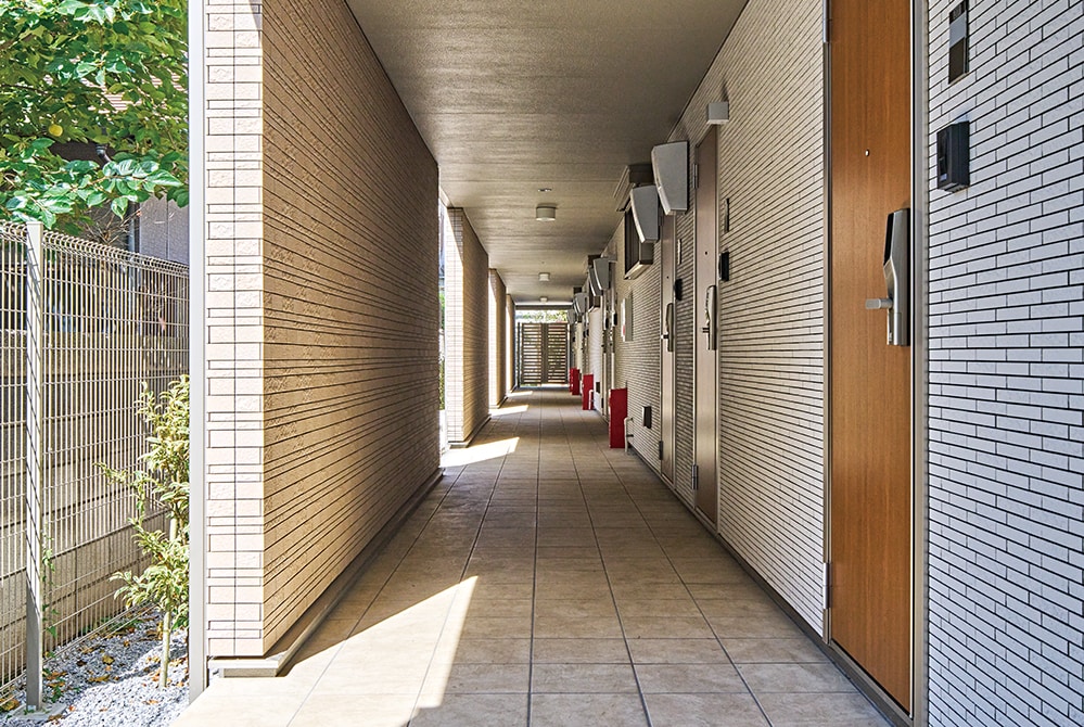 1階と2階の全10戸の玄関が並ぶタイル貼りの共用廊下。プライバシー保護と開放感が両立できる半屋外のつくりに。