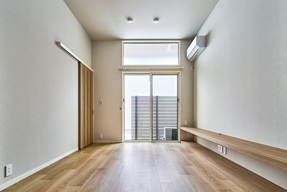 路地に面した北棟の住戸のLDK。目隠しフェンスで視線をカットしつつ、高窓と掃き出し窓を組み合わせた開口部からたっぷり光が入る。壁際に造作したカウンターはテレビ台などとして活用可能。