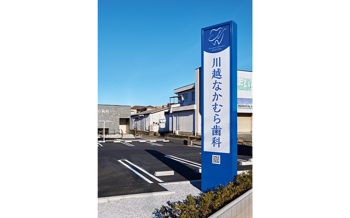 車椅子対応の駐車スペースも確保した建物前面の駐車場。道路沿いに立つ看板が視認性を高めている。