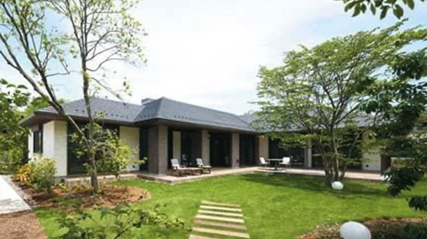 雑木林のような庭園を眺めて、ご夫婦で憩うリゾート感漂う平屋の落ち着きある邸宅の様子